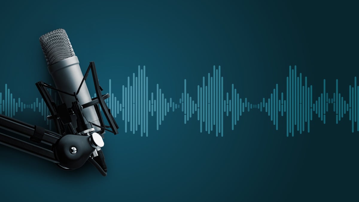 A microphone is set up for a podcast, showing sound wave patterns on a blue background.