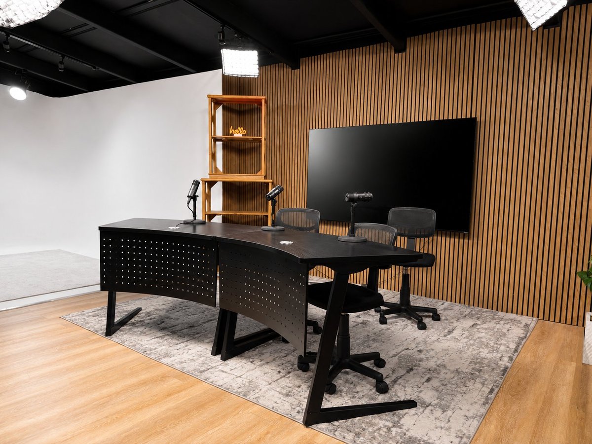 Modern office space with black desk, computer monitor, gaming chair, and wood accent wall with shelving unit.